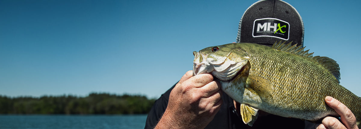 Man with MHX hat, holding up a fish