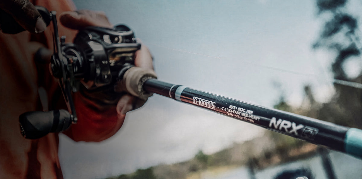 Angler gripping a G. Loomis NRX casting rod and baitcasting reel on the water